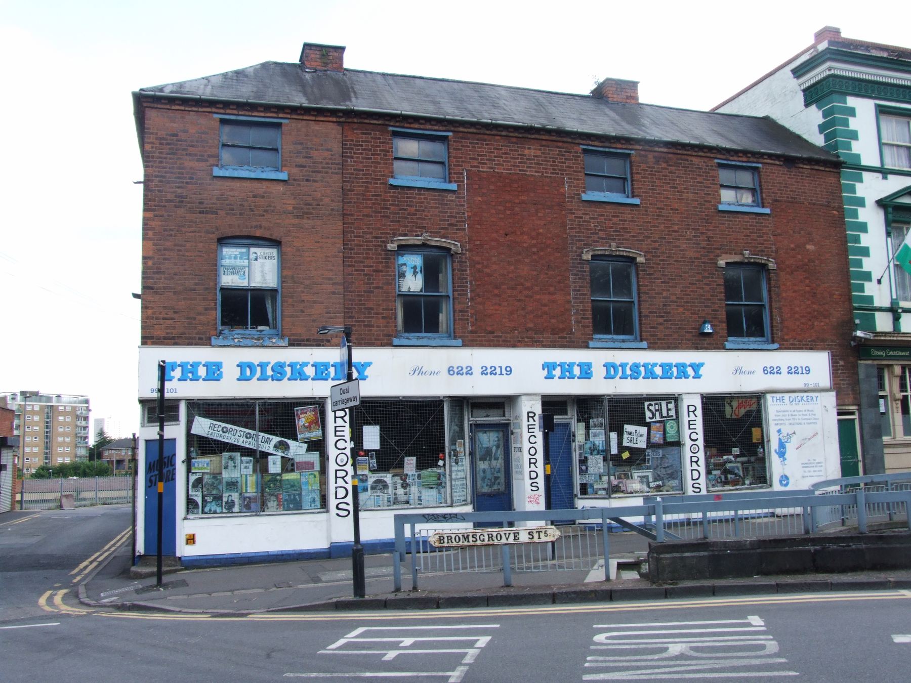 The Diskery shopfront at 99-102 Bromsgrove Street, Birmingham, with painted blue-on-cream signwriting and the corner Bromsgrove St sign visible